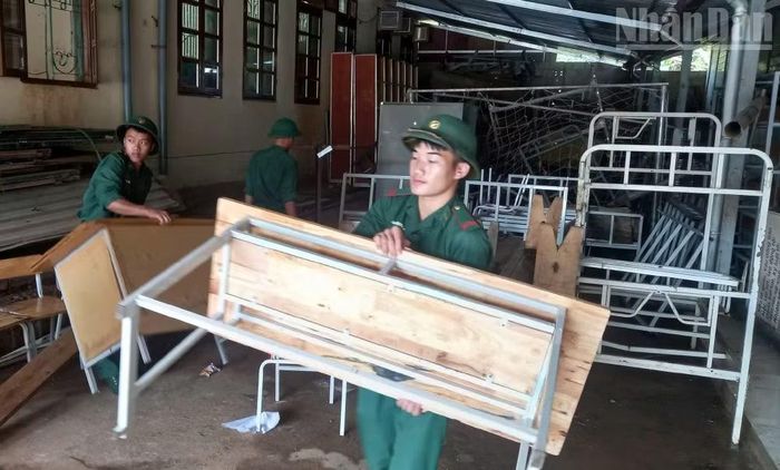 Cán bộ, chiến sĩ Đồn Biên phòng Cửa khẩu quốc tế Lóng Sập vệ sinh và sắp xếp bàn ghế giúp Trường phổ thông nội trú tiểu học và trung học cơ sở Lóng Sập. (Ảnh: QUÀNG HÙNG)