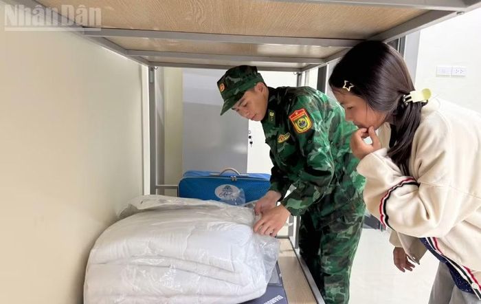 Cán bộ Đồn Biên phòng Mường Cai hướng dẫn các cháu học sinh nội trú về cách gấp chăn màn. (Ảnh: QUÀNG HÙNG)