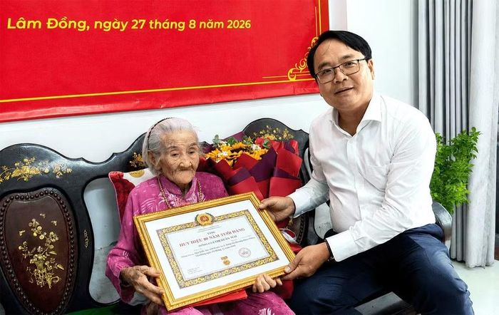 Phó Bí thư Thường trực Tỉnh ủy Lâm Đồng Đặng Hồng Sỹ trao Huy hiệu 80 năm tuổi Đảng cho đảng viên Lâm Thị Xuân Mai. (Ảnh: Báo Lâm Đồng)