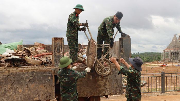 Cán bộ, chiến sĩ tham gia chở vôi vữa thừa ra khỏi các dãy nhà. Ảnh: HỮU PHÚC