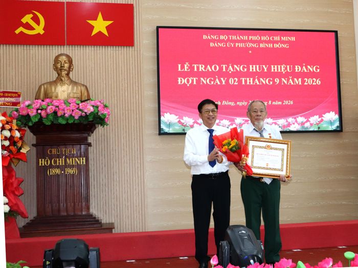  Bí thư Đảng ủy phường Bình Đông Võ Thành Khả trao Huy hiệu Đảng đến đảng viên. Ảnh THÁI PHƯƠNG. 