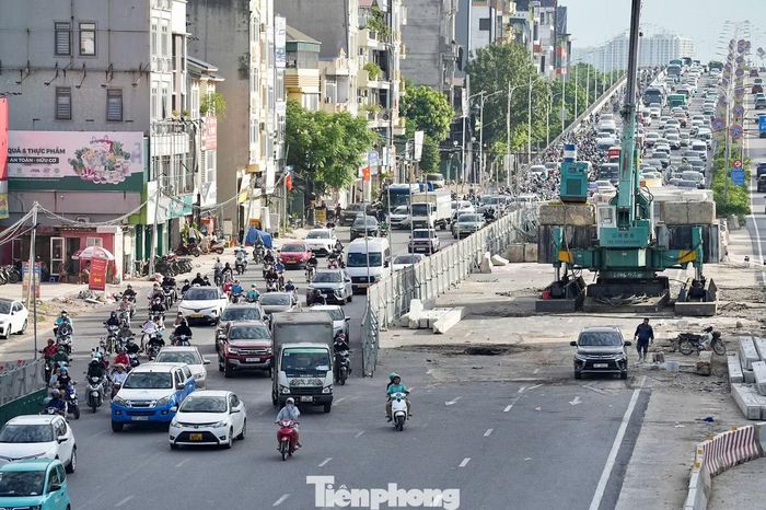 Tại khu vực nút giao Cổ Linh - Thạch Bàn, phương tiện xếp thành hàng dài chờ qua nút. Ôtô nối đuôi nhau, trong khi xe máy len qua những khoảng trống để tìm hướng di chuyển.