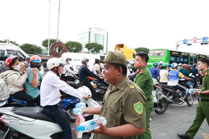 Dọc các giao lộ, lực lượng công an cùng dân phòng túc trực trao tận tay từng chai nước mát, tiếp sức cho người dân trên đường vội vã về quê.