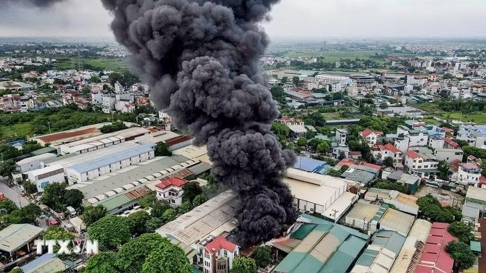 Cột khói đen dày đặc bốc lên từ khu vực xưởng nhựa; lực lượng chức năng triển khai nhiều mũi tiếp cận hiện trường để khống chế đám cháy. (Ảnh: TTXVN phát)