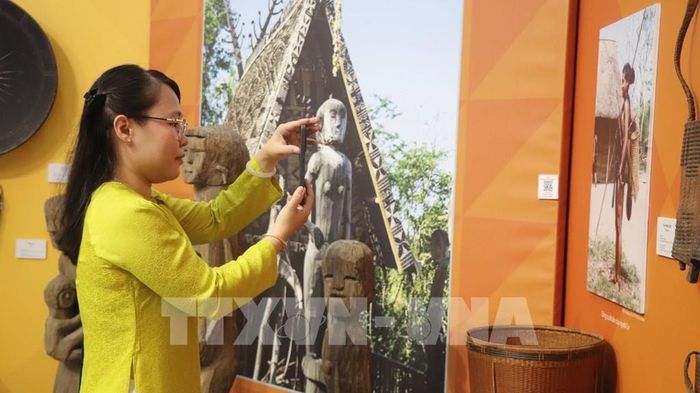 Khách tham quan thích thú check QR để tìm hiểu về văn hóa các dân tộc thiểu số. Ảnh: Nguyễn Hằng - TTXVN