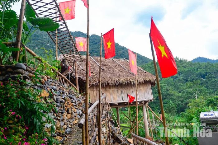 Những ngôi nhà nép mình dưới chân núi, phía trước là lá cờ đỏ sao vàng tung bay trong không khí rộn ràng của ngày lễ mừng Quốc khánh đang đến gần.