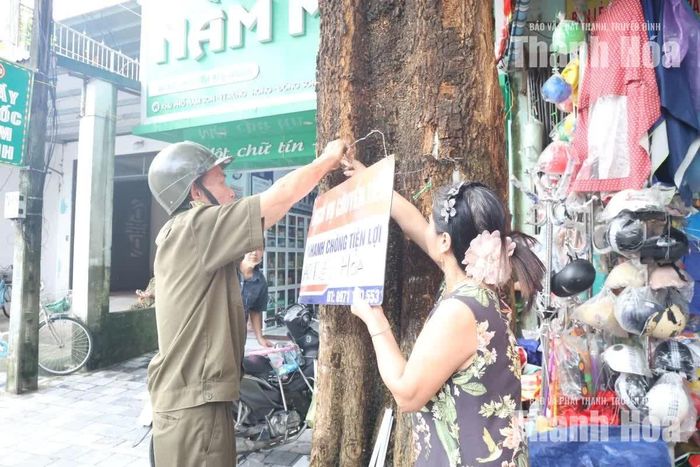 Người dân phối hợp cùng lực lượng cơ sở tháo dỡ biển quảng cáo treo không đúng quy định.