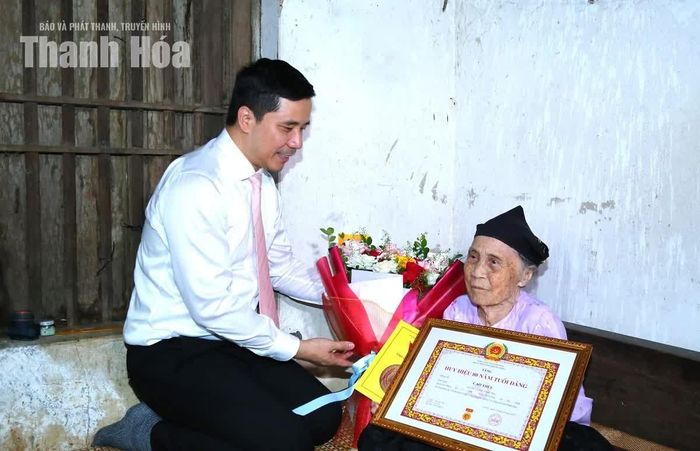 Phó Bí thư Thường trực Tỉnh ủy Nguyễn Hồng Phong trao Huy hiệu 80 năm tuổi Đảng, Quyết định của Ban Bí thư và tặng hoa chúc mừng đảng viên Cao Thị Ý.