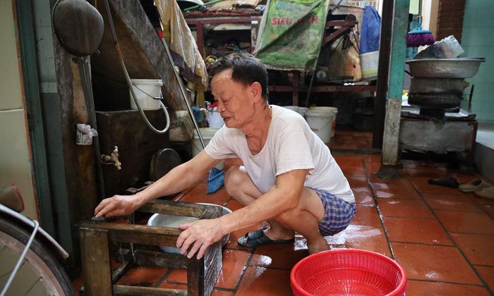  Ông Trịnh Đắc Thịnh, tổ dân phố Thổ Hà cọ rửa các vật dụng làm bánh đa nem bị ngập trong bùn nước. 
