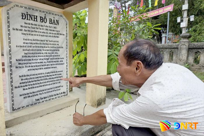 Ông Tán Kim, Trưởng ban Quản lý đình Bồ Bản giới thiệu thông tin ghi trên bia đá về sự kiện nhân dân Bồ Bản từ đình làng kéo đi giành chính quyền năm 1945. Ảnh: HÀN NGUYÊN