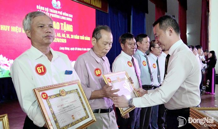Phó Bí thư Đảng ủy, Chủ tịch UBND phường Long Hưng Phan Huy Toàn trao quyết định của Ban Thường vụ Thành ủy Đồng Nai và gắn Huy hiệu Đảng cho các đảng viên. Ảnh: Xuân Nương