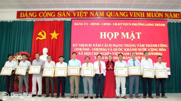 Thành ủy viên, Bí thư Đảng ủy, Chủ tịch HĐND phường Long Thành Nguyễn Hữu Nguyên (thứ 6 từ phải qua) và các đồng chí trong Thường trực Đảng ủy trao Huy hiệu Đảng cho các đảng viên. Ảnh: ĐPCC