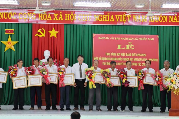 Phó Bí thư Thường trực Đảng ủy xã Phước Dinh trao Huy hiệu Đảng cho các đảng viên.