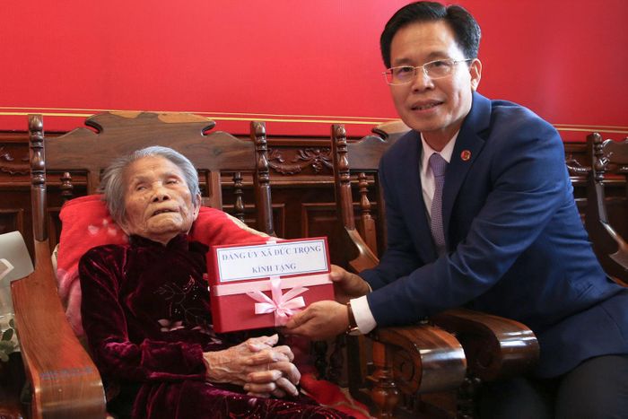 Đồng chí Trần Trung Hiếu, Bí thư Đảng ủy, Chủ tịch HĐND xã Đức Trọng tặng quà chúc mừng cho đảng viên Lê Thị Dục