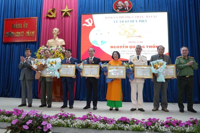 Thiếu tướng Trương Minh Đương, Giám đốc Công an tỉnh và đồng chí Phạm Kim Quang, Bí thư Đảng ủy Phường Cam Ly - Đà Lạt trao huy hiệu và hoa chúc mừng các đảng viên