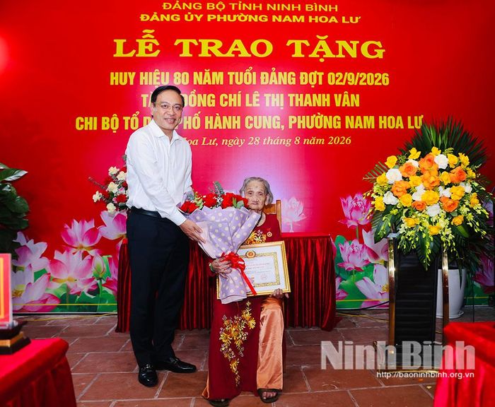 Đồng chí Đặng Thanh Sơn, Ủy viên Ban Thường vụ Tỉnh ủy, Phó Chủ tịch UBND tỉnh tặng hoa chúc mừng đồng chí Lê Thị Thanh Vân, đảng viên Chi bộ tổ dân phố Hành Cung, Đảng bộ phường Nam Hoa Lư.