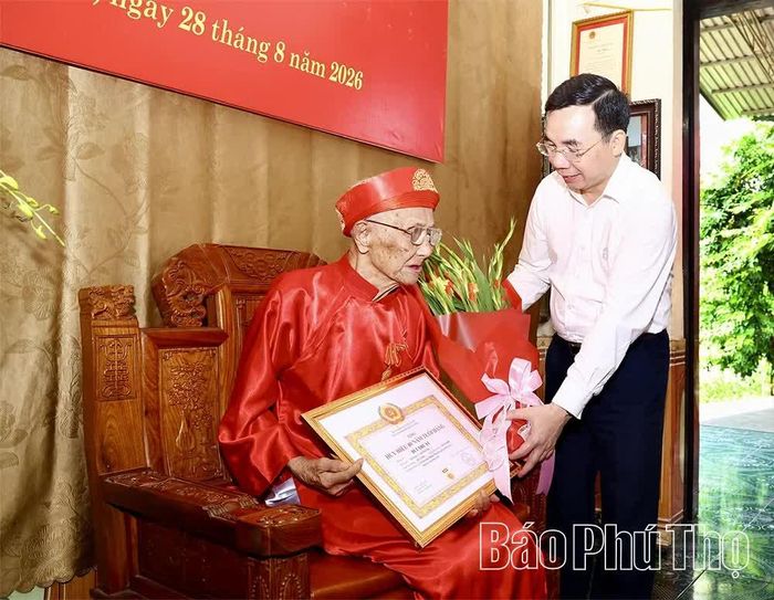 Phó Bí thư Tỉnh ủy Bùi Huy Vĩnh trao Huy hiệu 80 năm tuổi Đảng và tặng hoa chúc mừng đảng viên lão thành Bùi Thuật.