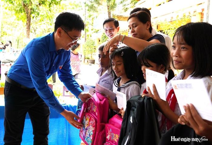 Bí thư Chi đoàn Báo và Phát thanh, Truyền hình Huế Võ Đức Quang trao tặng ba lô cho các em học sinh. 
