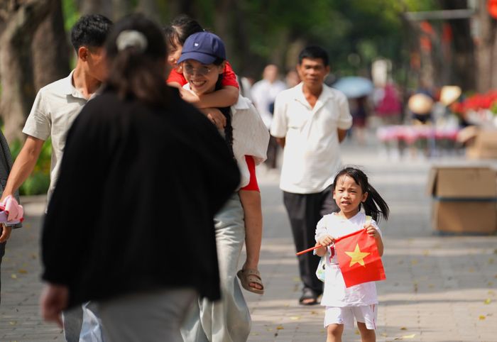 Một em nhỏ trên tay với lá cờ Tổ quốc thắm tươi.