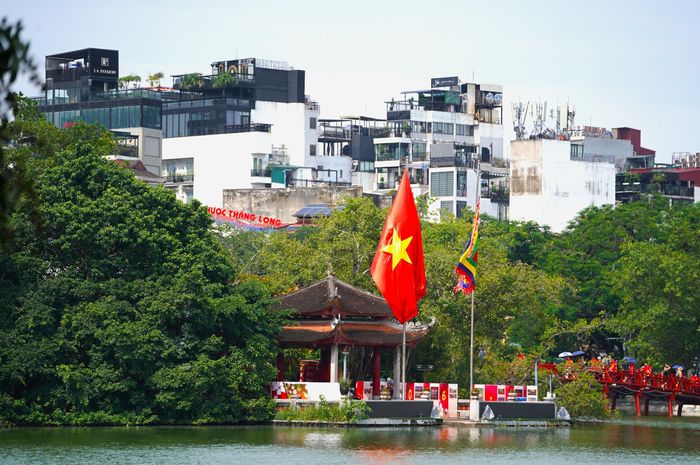 Trong không gian cổ kính của đền Ngọc Sơn, lá cờ Tổ quốc đỏ thắm tung bay đầy nổi bật, làm tăng thêm vẻ trang nghiêm và tinh thần tự hào dân tộc.
