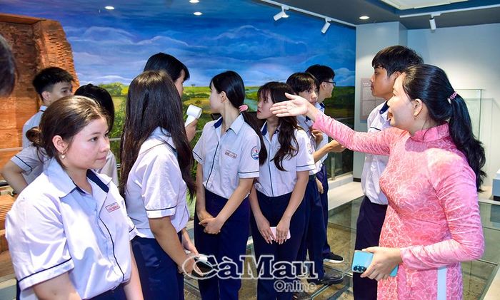 Thuyết minh viên giới thiệu với học sinh giá trị lịch sử, văn hoá của Di tích quốc gia đặc biệt khảo cổ Vĩnh Hưng.