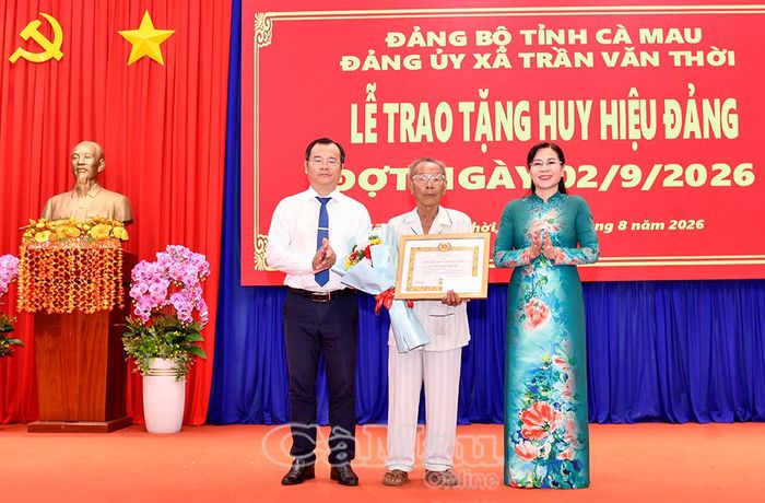 Phó Chủ tịch Thường trực HĐND tỉnh Lê Thị Nhung và Bí thư Đảng uỷ Xã Trần Văn Thời Nguyễn Thế Châu trao Huy hiệu 60 năm tuổi Đảng và tặng hoa chúc mừng đồng chí Nguyễn Việt Trung.