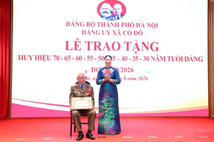 Đồng chí Nguyễn Thị Kim Oanh, Bí thư Đảng ủy, Chủ tịch HĐND xã Cổ Đô trao tặng Huy hiệu 70 năm tuổi Đảng cho đồng chí Nguyễn Viết Đức, sinh hoạt tại Chi bộ thôn Tân Phong. Ảnh: Hồng Đạt