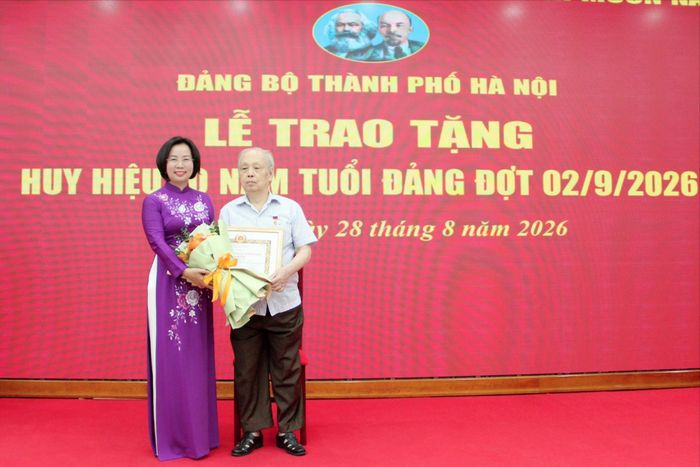 Ủy viên Ban Thường vụ Thành ủy, Bí thư Đảng ủy, Chủ tịch Ủy ban MTTQ Việt Nam thành phố Hà Nội Bùi Huyền Mai trao Huy hiệu 70 năm tuổi Đảng tặng đồng chí Hạ Bá Đoàn. Ảnh: Lê Phương