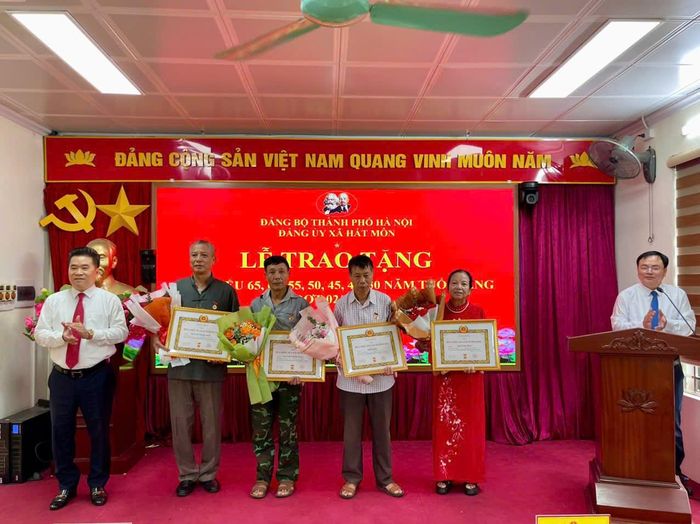 Chủ tịch UBND xã Hát Môn Lý Hoàng Kiên trao Huy hiệu Đảng tặng đảng viên. Ảnh: Đoàn Điệp