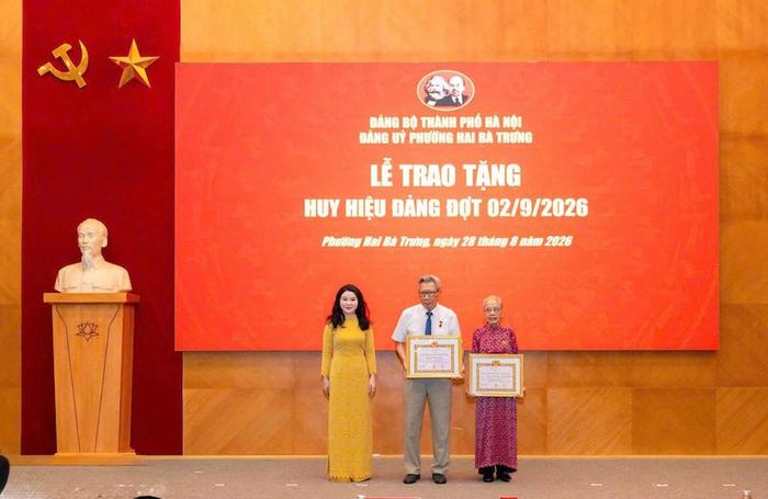 Bí thư Đảng ủy, Chủ tịch HĐND phường Hai Bà Trưng Chu Hồng Minh trao Huy hiệu 65 năm tuổi Đảng tặng đảng viên. Ảnh: NQ