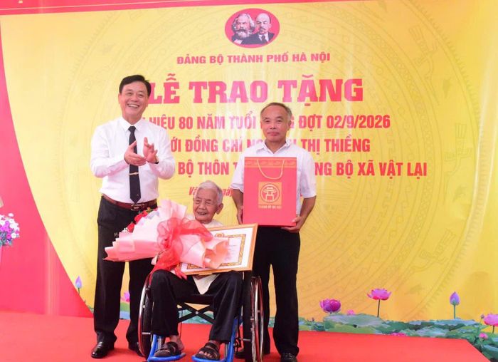 Trung tướng Đào Văn Nhận, Ủy viên Ban Thường vụ Thành ủy, Tư lệnh Bộ Tư lệnh Thủ đô Hà Nội trao Huy hiệu 80 năm tuổi Đảng tặng đảng viên lão thành Nguyễn Thị Thiềng. Ảnh: Hữu Thu
