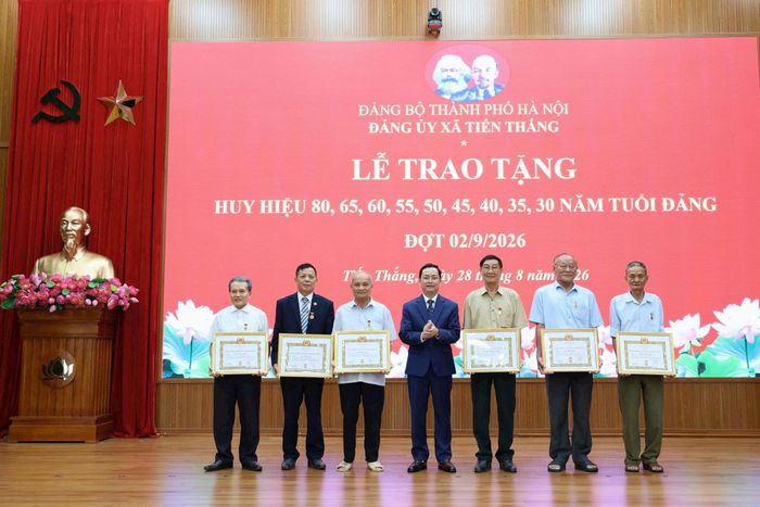 Phó Bí thư Thường trực Đảng ủy, Chủ tịch HĐND xã Đinh Ngọc Thức trao Huy hiệu Đảng cho các đảng viên. Ảnh PV