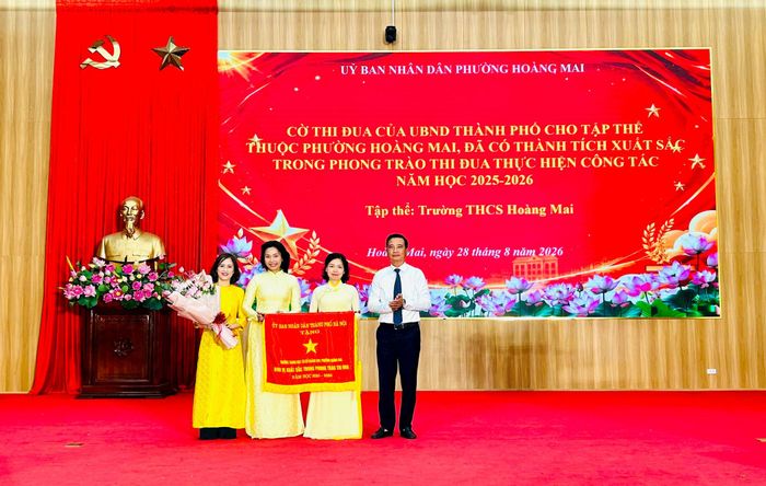 Bí thư Đảng ủy, Chủ tịch HĐND phường Hoàng Mai Nguyễn Xuân Linh trao Cờ thi đua của UBND Thành phố tặng tập thể Trường THCS Hoàng Mai. Ảnh: Trần Oanh