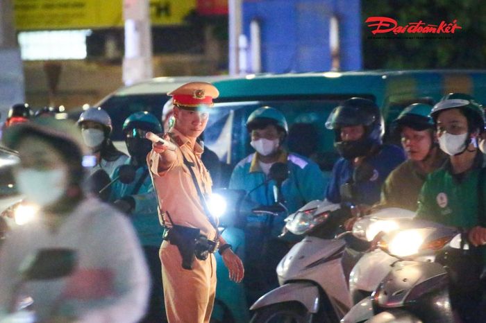 Đêm xuống khi ánh đèn xe phủ kín mặt đường. Giữa tiếng còi, tiếng động cơ và khói bụi, những cán bộ, chiến sĩ vẫn trực tiếp di chuyển giữa dòng phương tiện để điều tiết. Mỗi hiệu lệnh đưa ra là một lần họ phải quan sát nhanh, phán đoán hướng di chuyển của hàng trăm phương tiện đang cùng lúc qua nút giao.