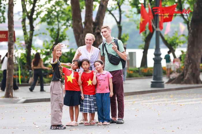 Du khách quốc tế thích thú khi chụp ảnh cùng các em nhỏ tại khu vực Hồ Gươm