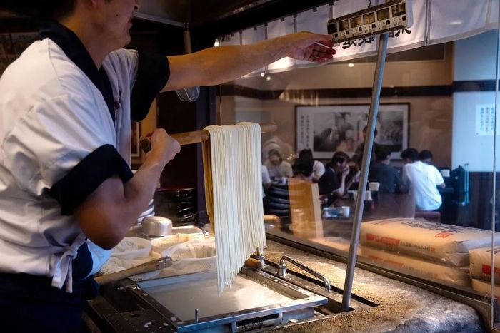  Một nhân viên đang chuẩn bị mì udon tại nhà hàng ở Tokyo. Ảnh: Louise Delmotte/Bloomberg. 