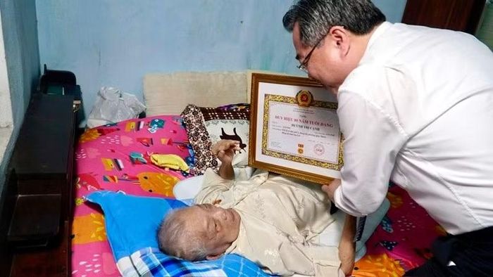 Đồng chí Nguyễn Thanh Nghị trao Huy hiệu 80 năm tuổi Đảng cho đồng chí Huỳnh Thị Cạnh tại nhà riêng. (Ảnh: SỸ THẮNG)