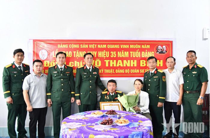  Đại tá Cao Minh Tâm, Ủy viên Ban Thường vụ Đảng ủy, Phó chính ủy Bộ CHQS tỉnh An Giang trao Huy hiệu 35 năm tuổi Đảng tặng Đại tá Võ Thanh Bình, nguyên Phó chỉ huy trưởng Bộ CHQS tỉnh. 