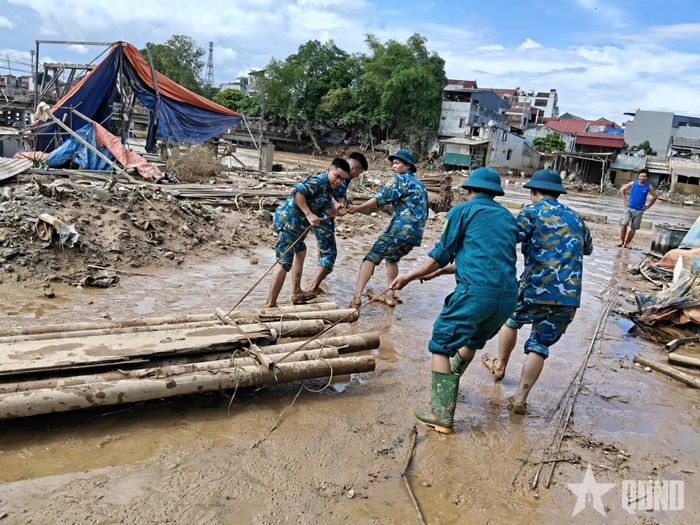 Phối hợp cùng lực lượng dân quân tự vệ địa phương dọn dẹp rác sau lũ. 
