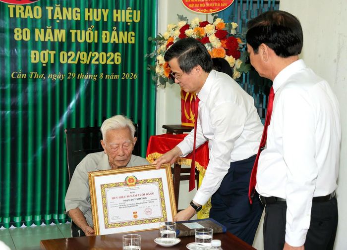 Thay mặt lãnh đạo Đảng, Nhà nước, ông Đoàn Minh Huấn trao Huy hiệu 80 năm tuổi Đảng do Ban Bí thư tặng ông Phạm Duy Khương. (Ảnh: Minh Trung)