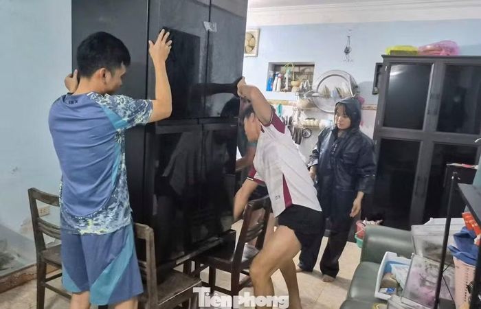 Người dân bì bõm lội nước về nhà và kê cao tài sản tránh thiệt hại.