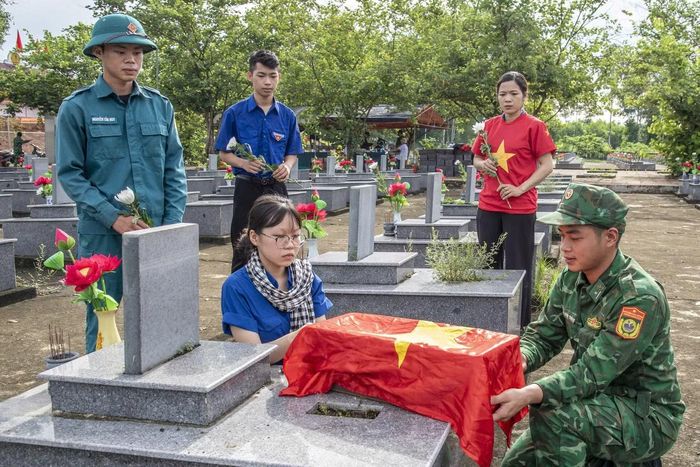 Các đoàn viên thanh niên kính cẩn nghiêng mình trước khi quan tài được chôn cất trở lại. (Ảnh: Lê Văn Chương)