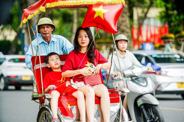 Hai mẹ con mặc áo cờ đỏ, chọn xích lô đi dạo phố trong ngày đầu tiên kỳ nghỉ lễ.