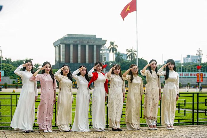 Một nhóm các bạn nữ trẻ mặc áo dài, chụp ảnh trang nghiêm trước Quảng trường Ba Đình.