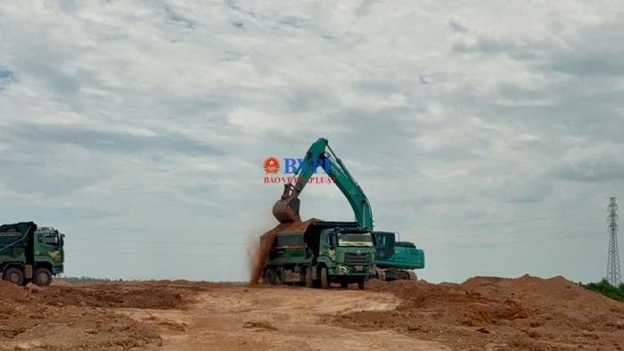  Máy múc đang múc đất đổ lên xe có tải trọng lớn.