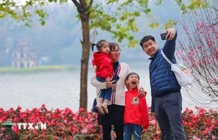 Cả gia đình cùng nhau ghi lại khoảnh khắc của mùa Xuân bên hồ Gươm. (Ảnh: Thanh Tùng/TTXVN)
