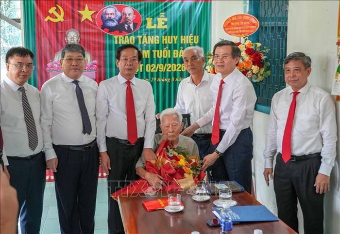 Ông Đoàn Minh Huấn, Ủy viên Bộ Chính trị, Giám đốc Học viện Chính trị Quốc gia Hồ Chí Minh trao Huy hiệu 80 năm tuổi Đảng cho đảng viên Phạm Duy Khương. Ảnh: Thanh Liêm - TTXVN