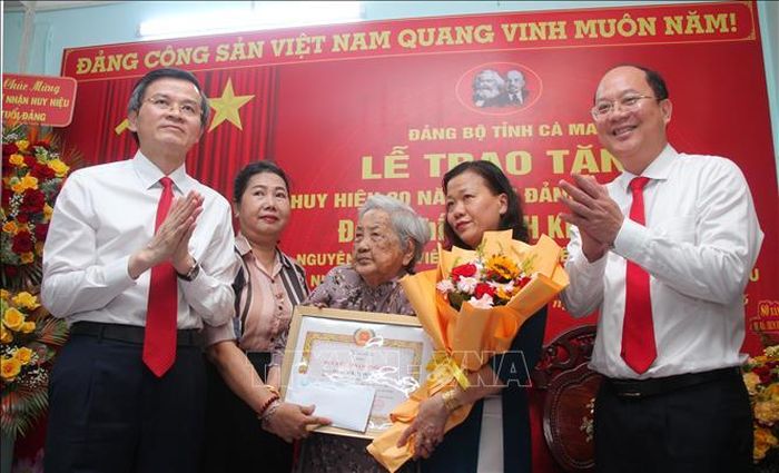 Đồng chí Đoàn Minh Huấn, Ủy viên Bộ Chính trị, Giám đốc Học viện Chính trị quốc gia Hồ Chí Minh (ngoài cùng, bên trái) và đồng chí Nguyễn Hồ Hải, Ủy viên Trung ương Đảng, Bí thư Tỉnh ủy, Trưởng Đoàn đại biểu Quốc hội tỉnh Cà Mau (bên phải) chúc mừng đồng chí Quách Kim Tuyến nhận Huy hiệu 80 năm tuổi Đảng. Ảnh: Chanh Đa/TTXVN