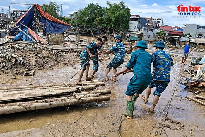 Cán bộ, chiến sĩ Trạm Ra đa 59 cùng lực lượng tại chỗ di chuyển cây gỗ, vật cản, khơi thông khu vực bị ảnh hưởng bởi mưa lũ.