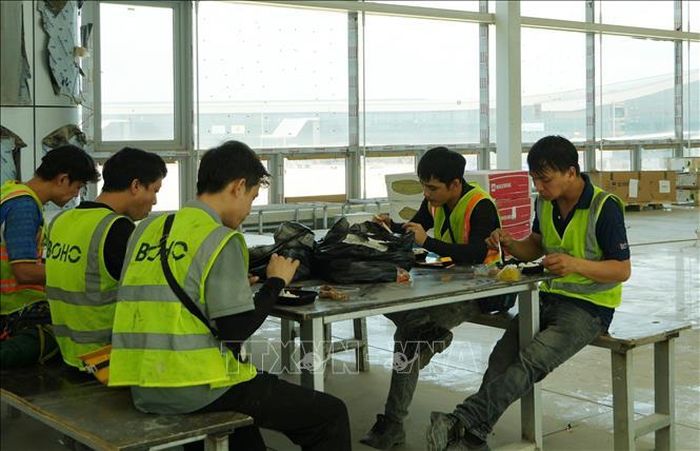 Người lao động tranh thủ giờ nghỉ ăn cơm trưa tại công trường sân bay Long Thành.
